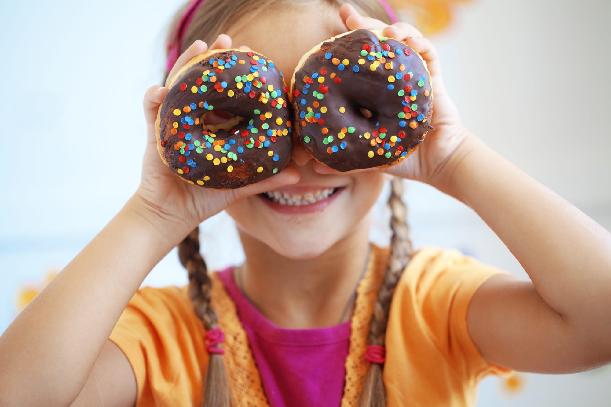 little girl holding donuts over her eyes