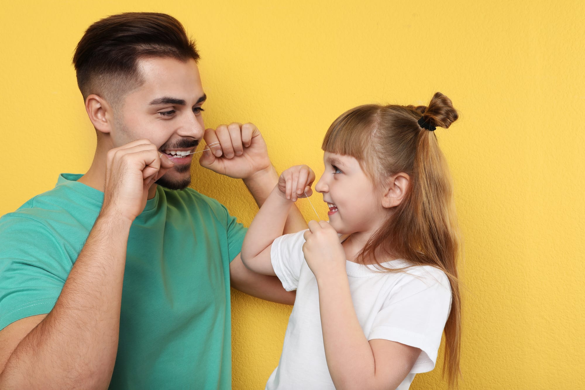 father and daughter flossing
