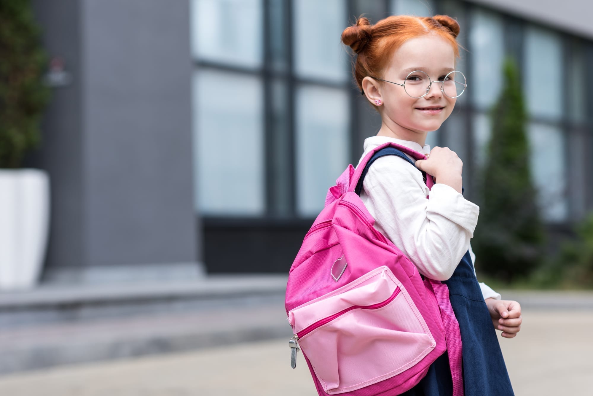 little girl holding backpack over shoulder