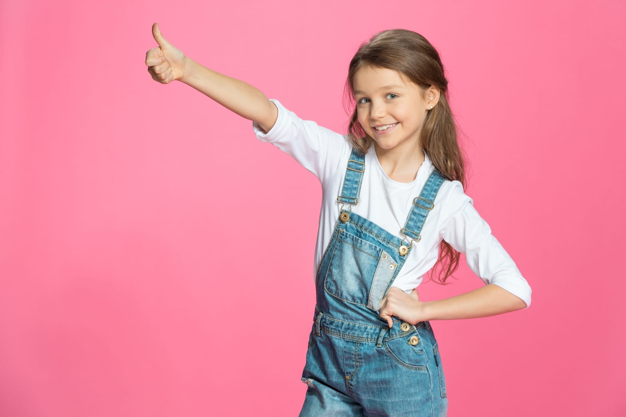little girl with thumbs up on pink background