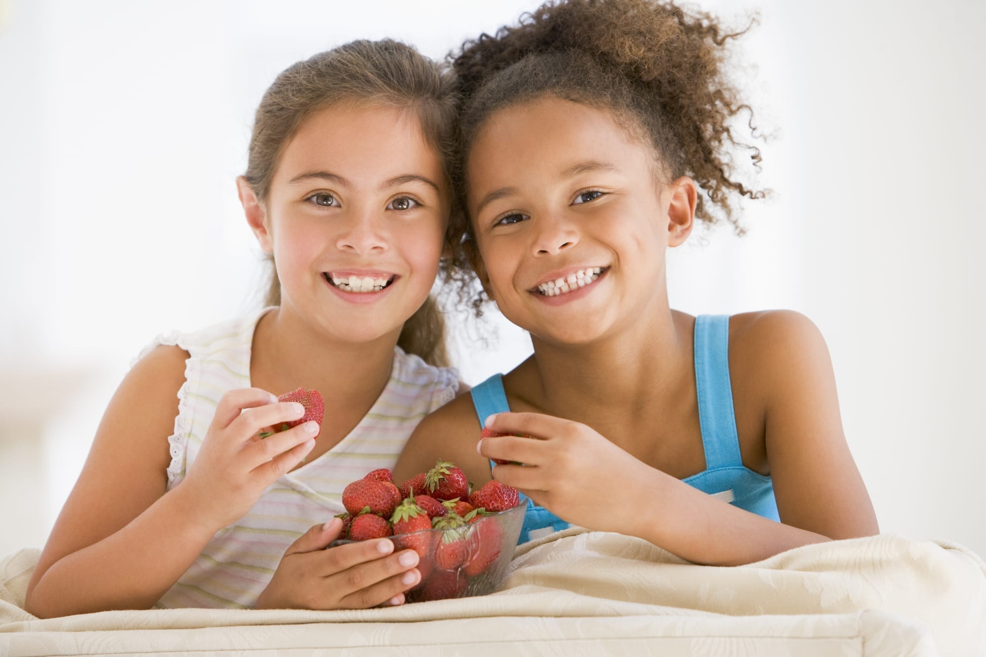 two little girls eating strawberries