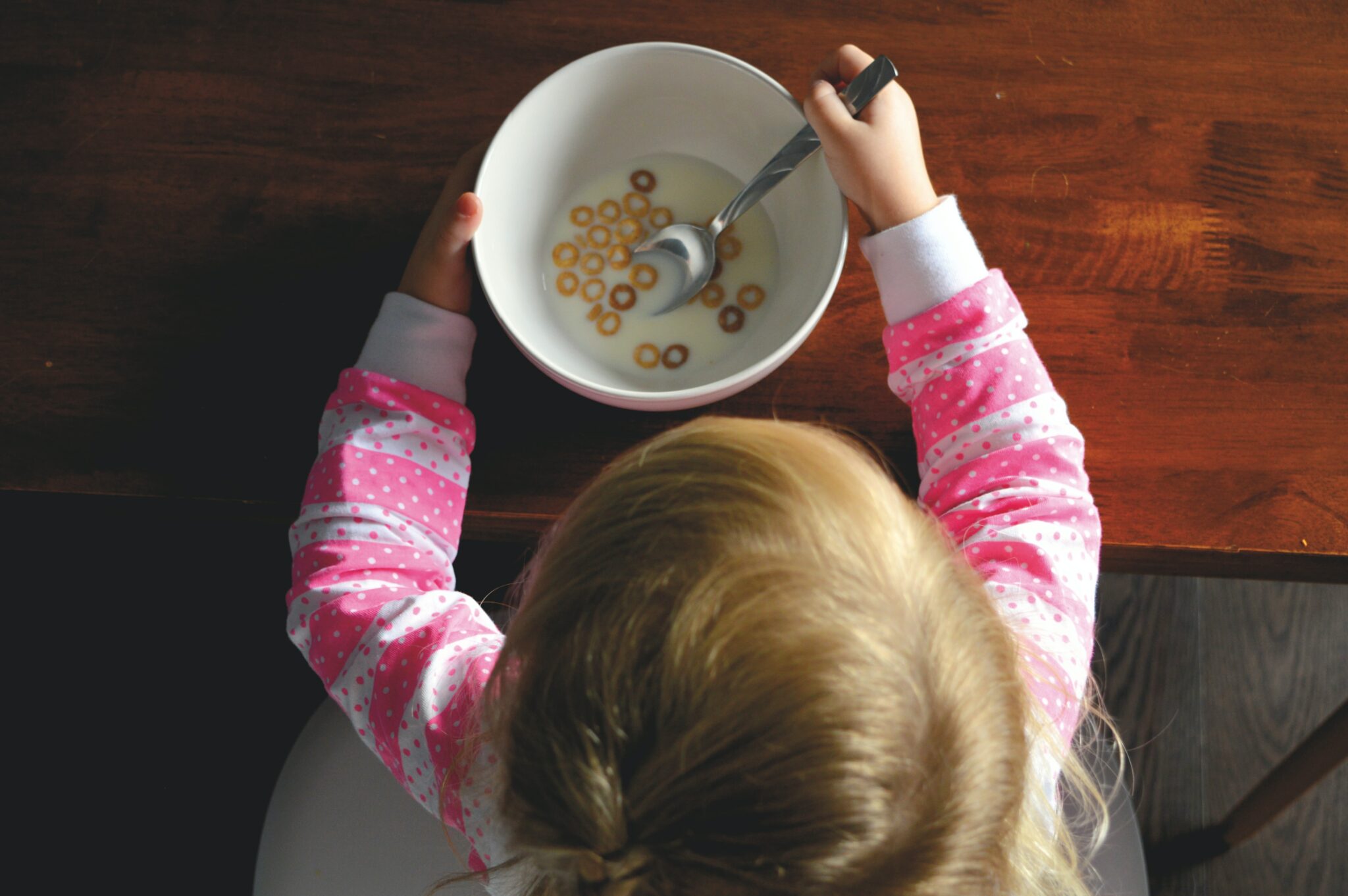 young girl with a bowl of cereal for breakfast