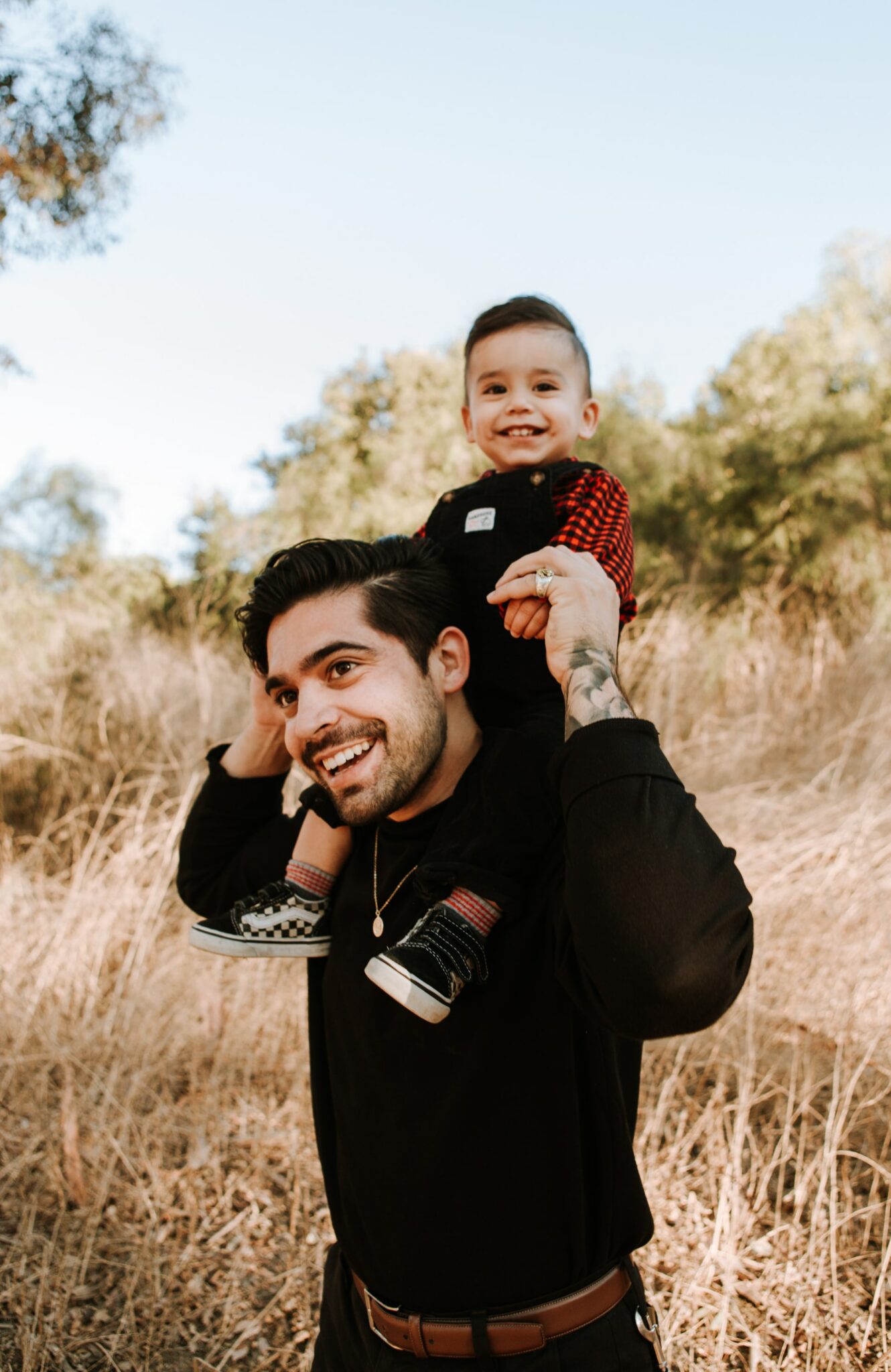 dad holding son on his shoulders in field