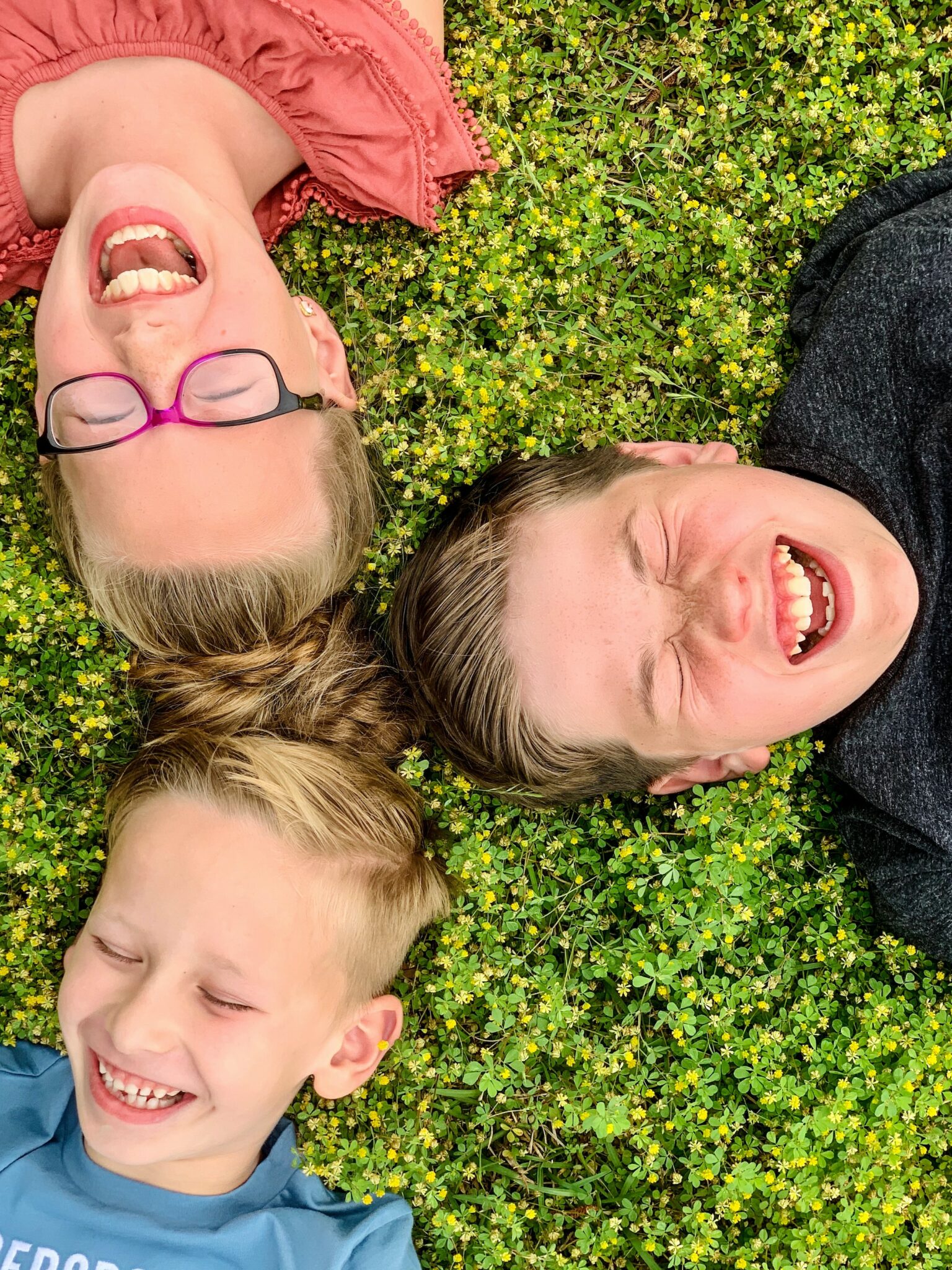 Three laughing children lying on the grass